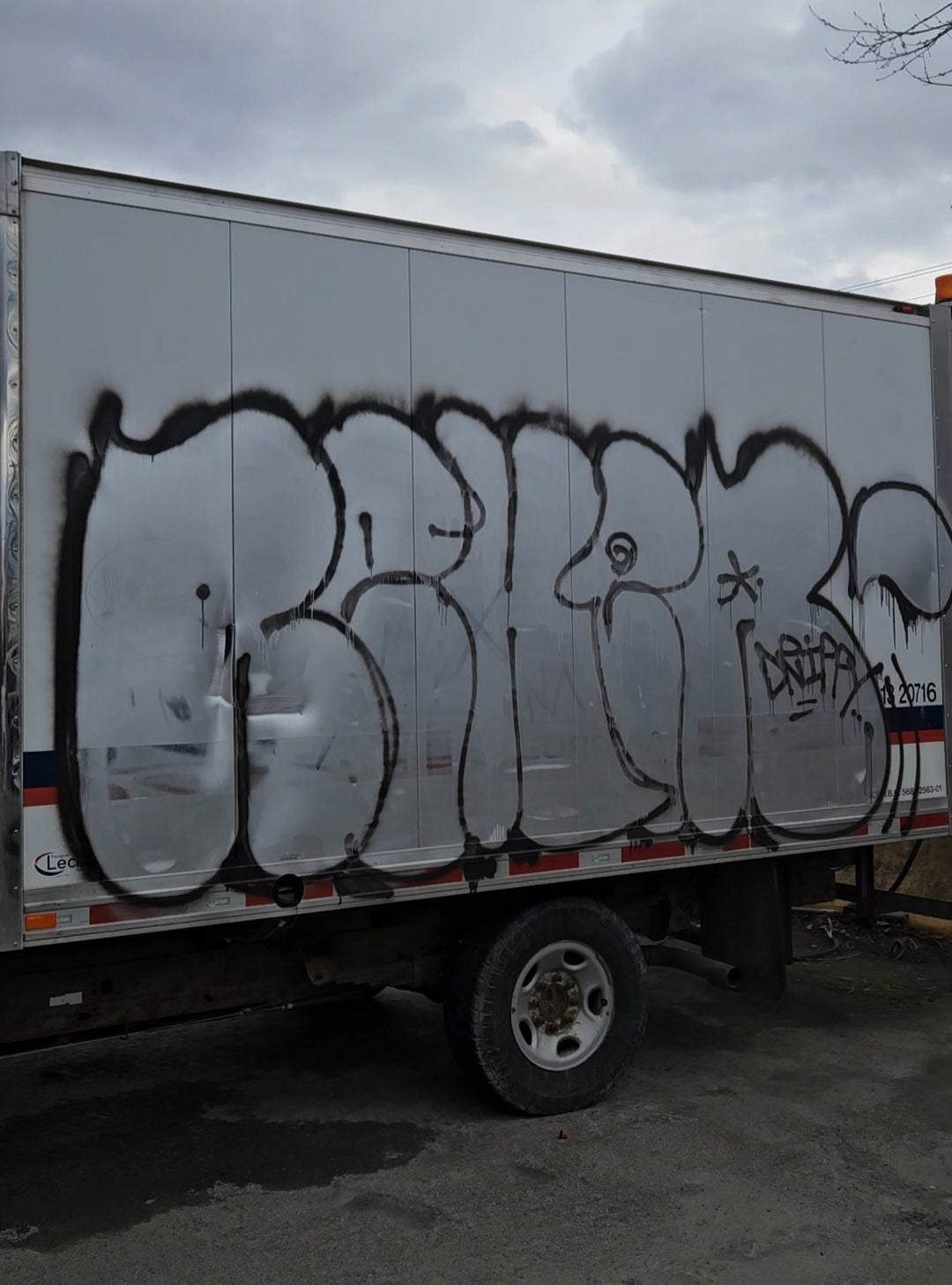 L'image présente un tag gris argent avec des contours noirs apposé sur un camion cube.